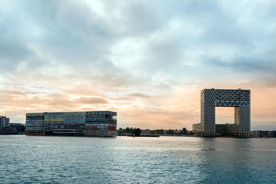 Buildings by river against sky