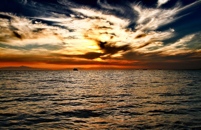 Scenic view of sea against dramatic sky during sunset