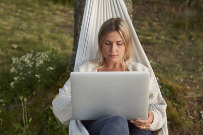 Woman using laptop on hammock