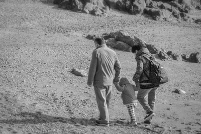 Family with holding hands while walking on shore at beach