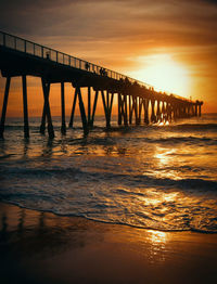 Pier over sea against sky during sunset