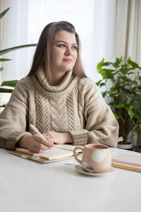 Portrait of young woman reading book at table