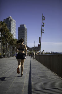 Rear view of woman walking on footpath against sky