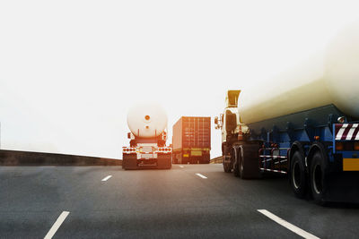 Vehicles on road against clear sky