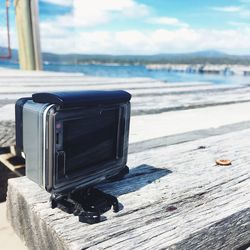 Close-up of camera by sea against sky