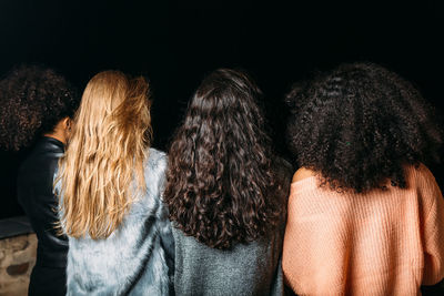 Rear view of friends standing against sky at night