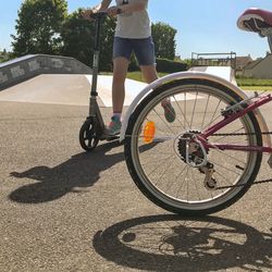 Low section of woman riding bicycle on sunny day