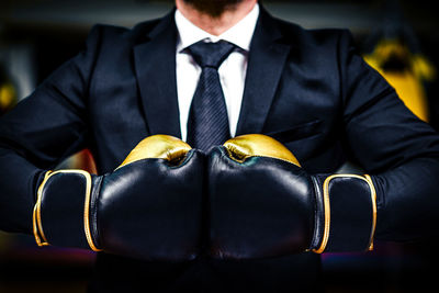 Midsection of businessman wearing boxing gloves