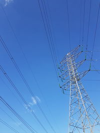 Low angle view of electricity pylon against blue sky