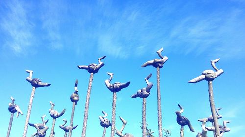 Low angle view of seagulls perching on blue sky