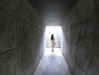 Rear view of woman walking in tunnel