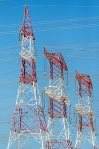 Low angle view of electricity pylon against blue sky