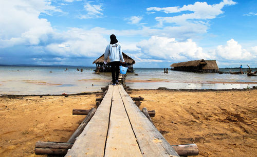 Rear view of woman standing on jetty against sea