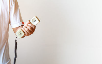 Close-up of hand holding mobile over white background