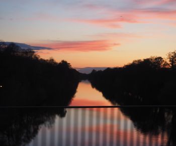 Reflection of trees in water at sunset