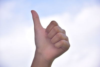 Close-up of human hand against sky