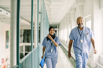 Portrait of coworkers talking while walking in corridor at hospital