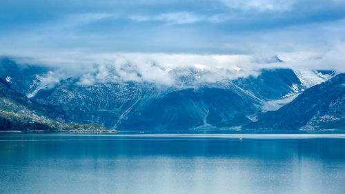 Scenic view of lake by snowcapped mountains against sky