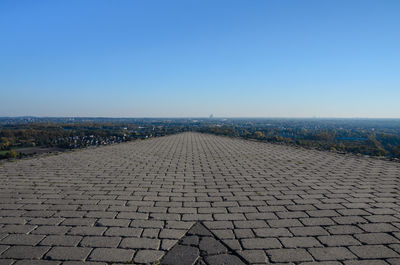 Cobblestone street against clear blue sky