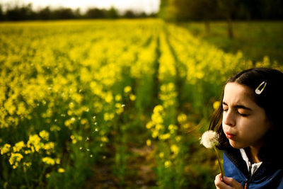 Portrait of woman with yellow flower in field
