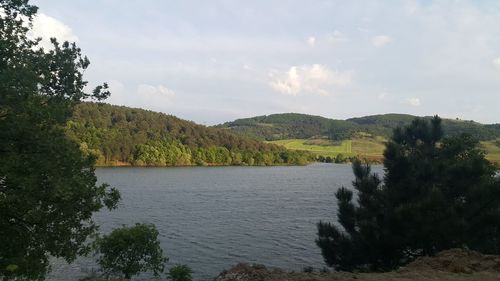 Scenic view of river by mountains against sky