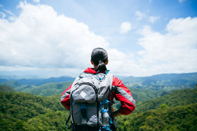 Rear view of man standing on mountain against sky