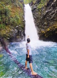 Rear view of man standing against waterfall