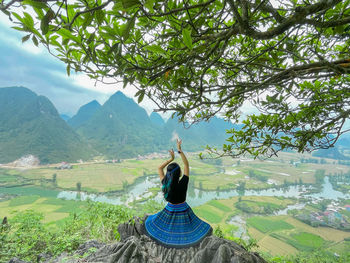 Woman with arms raised on mountain against sky