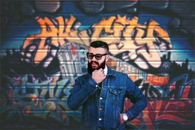 Bearded young man standing against graffiti wall