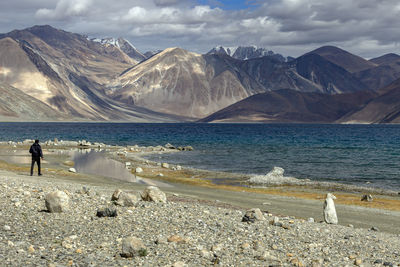 Scenic view of sea by mountains against sky