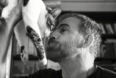 Close-up of man and cat rubbing noses at home