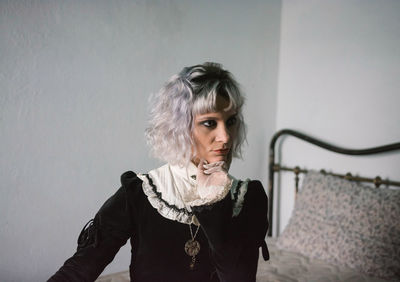 Portrait of young woman standing against wall