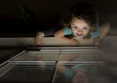 High angle view of girl climbing on window at home