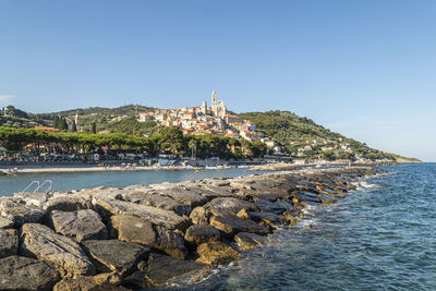 Scenic view of sea by townscape against clear sky