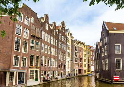 Canal amidst buildings against sky in city