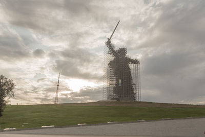 Low angle view of buildings on field against cloudy sky