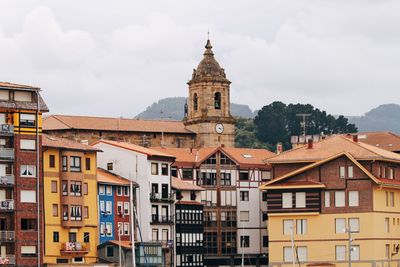 Buildings in town against cloudy sky