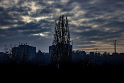 Silhouette trees and buildings against sky at sunset