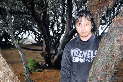 Portrait of boy standing by tree trunk