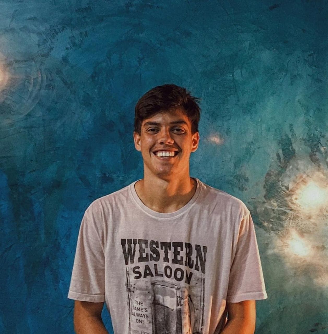 PORTRAIT OF SMILING YOUNG MAN STANDING AGAINST BLUE BACKGROUND