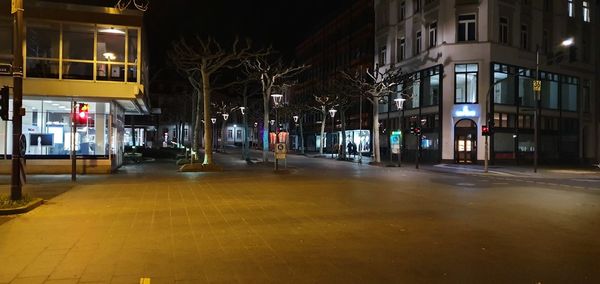 Illuminated street amidst buildings in city at night