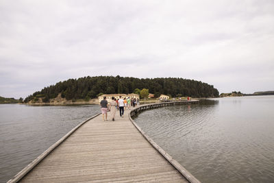 Rear view of people walking on lake against sky