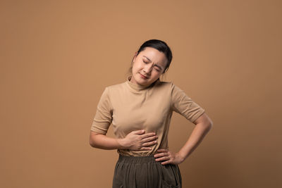 Young woman standing against yellow background
