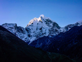 Scenic view of snowcapped mountains against clear blue sky