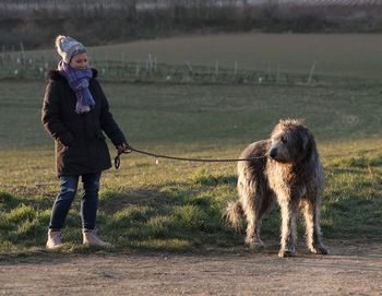 Woman with irish wolfhound on field against sky