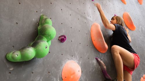 Low angle view of mid adult woman climbing wall