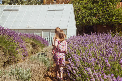 Rear view of kids running on flower field