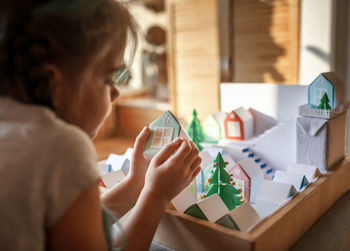 Origami advent calendar, paper craft. girl looking upon paper houses with number and paper tree