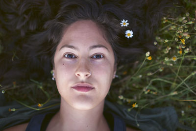 Portrait of a young woman lying on the grass with flowers in her hair person