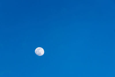 Low angle view of moon against clear blue sky